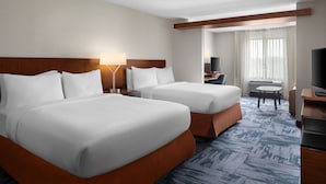 A hotel room with two beds, a desk, a TV, and a window with curtains.