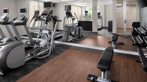 A gym with treadmills, elliptical machines, and weight benches.