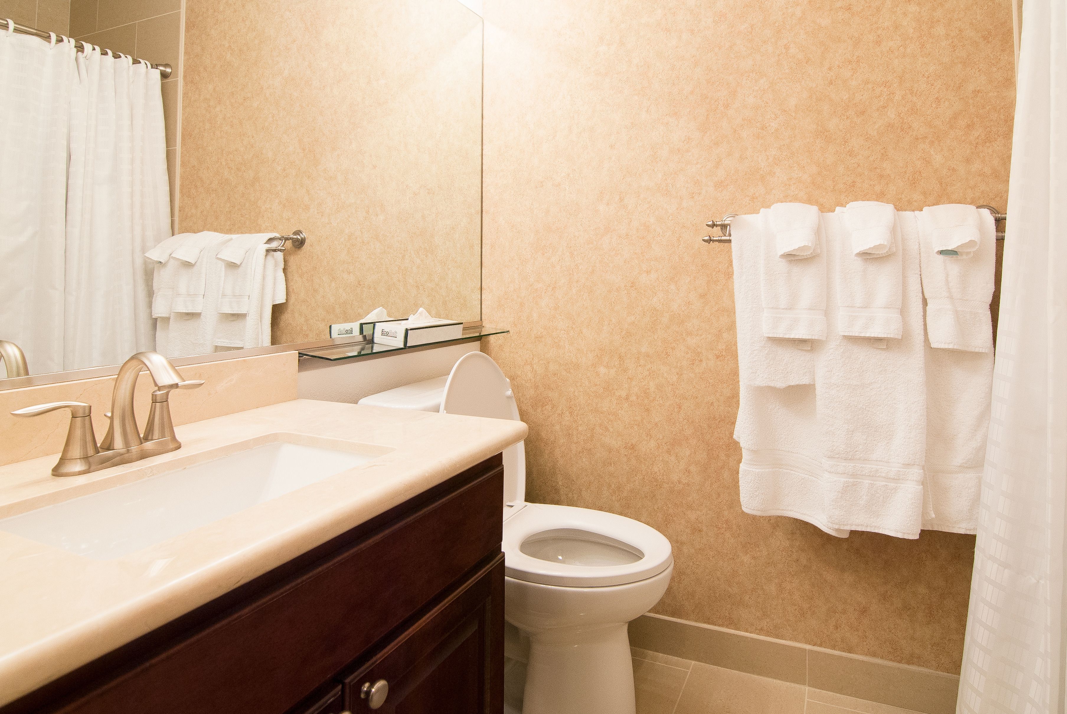 A bathroom with a sink, mirror, toilet, and towel rack.