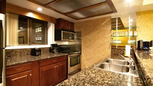 Una cucina con piani in granito, elettrodomestici in acciaio inossidabile, mobili in legno e forno a microonde integrato.