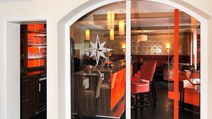 A lounge area with a glass partition, a wooden counter, and red seating. - Hotel & Restaurant Nordstern (Neuharlingersiel)