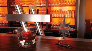 A bar area with a candle in a glass holder, a metal star decoration, and shelves with wine glasses. - Hotel & Restaurant Nordstern (Neuharlingersiel)