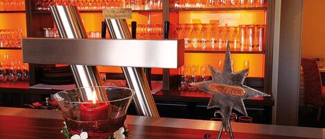A bar area with a candle in a glass holder, a metal star decoration, and shelves with wine glasses.