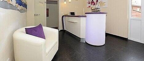 Un espace d’accueil avec un canapé blanc, un comptoir de réception et une œuvre d’art accrochée au mur.