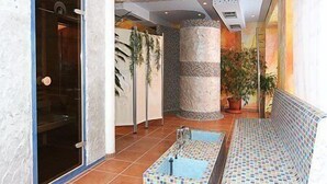 A spa area with a tiled floor, a stone column, a bench, and potted plants. - Hotel & Restaurant Nordstern (Neuharlingersiel)