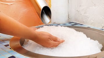 Eine Hand schöpft Eis in eine Schüssel.