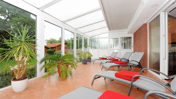 A sunlit patio with lounge chairs, potted plants, and a view of the surrounding area. - Hotel & Restaurant Nordstern (Neuharlingersiel)