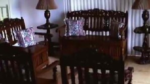 A living room with a wooden sofa, two armchairs, and a coffee table. There is a lamp on each side of the sofa. - DM Residente Tagaytay (Lemery)