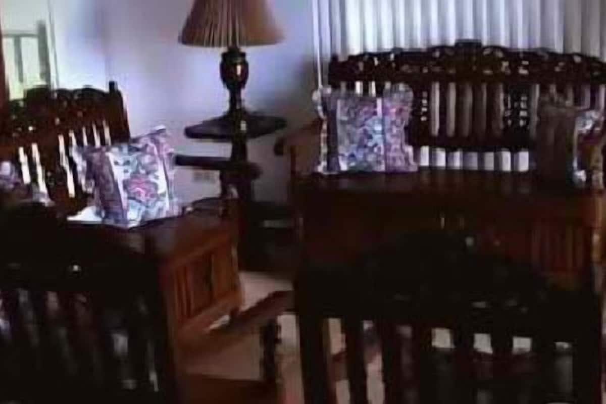 Un salon avec un canapé en bois, deux fauteuils et une table basse. Il y a une lampe de chaque côté du canapé.