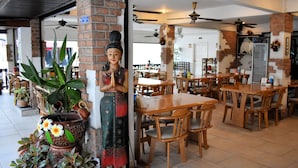 A restaurant with brick pillars, wooden tables, and ceiling fans. - Klein Heidelberg (Pattaya)