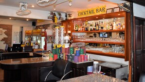 A cocktail bar with a variety of bottles and glasses on shelves, a cash register, and a seating area with a counter. - Klein Heidelberg (Pattaya)