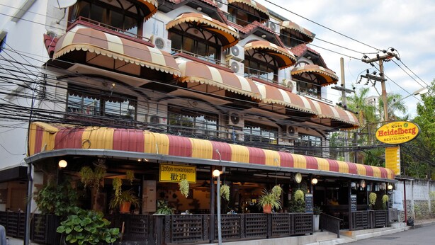 A multi-story building with a distinctive architectural design featuring curved balconies and a striped awning. - Klein Heidelberg (Pattaya)