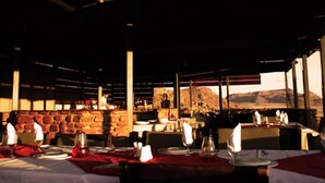 An outdoor restaurant with tables set for dining, stone walls, and a view of the mountains.