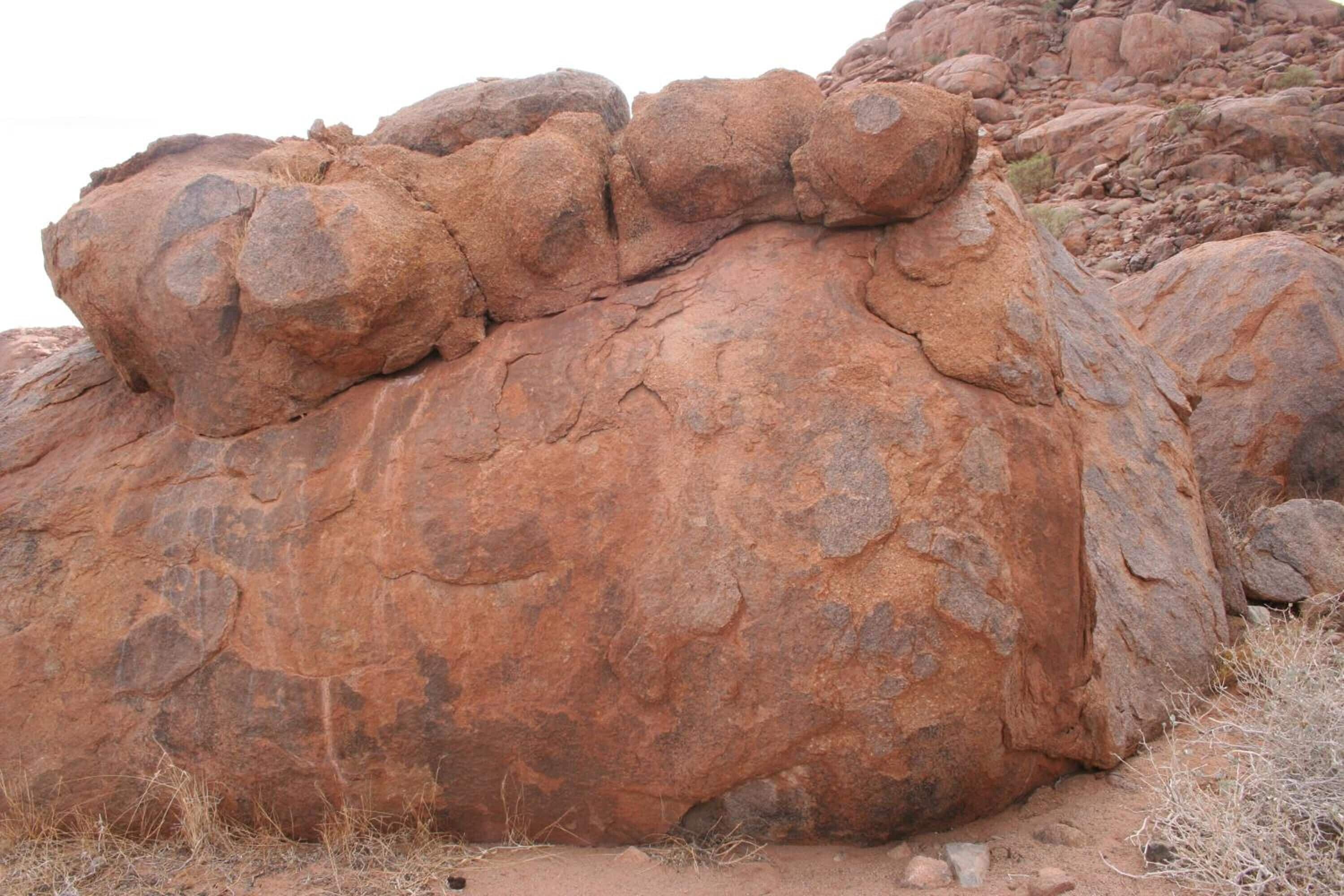 A large reddish-brown rock formation with a rugged surface.
