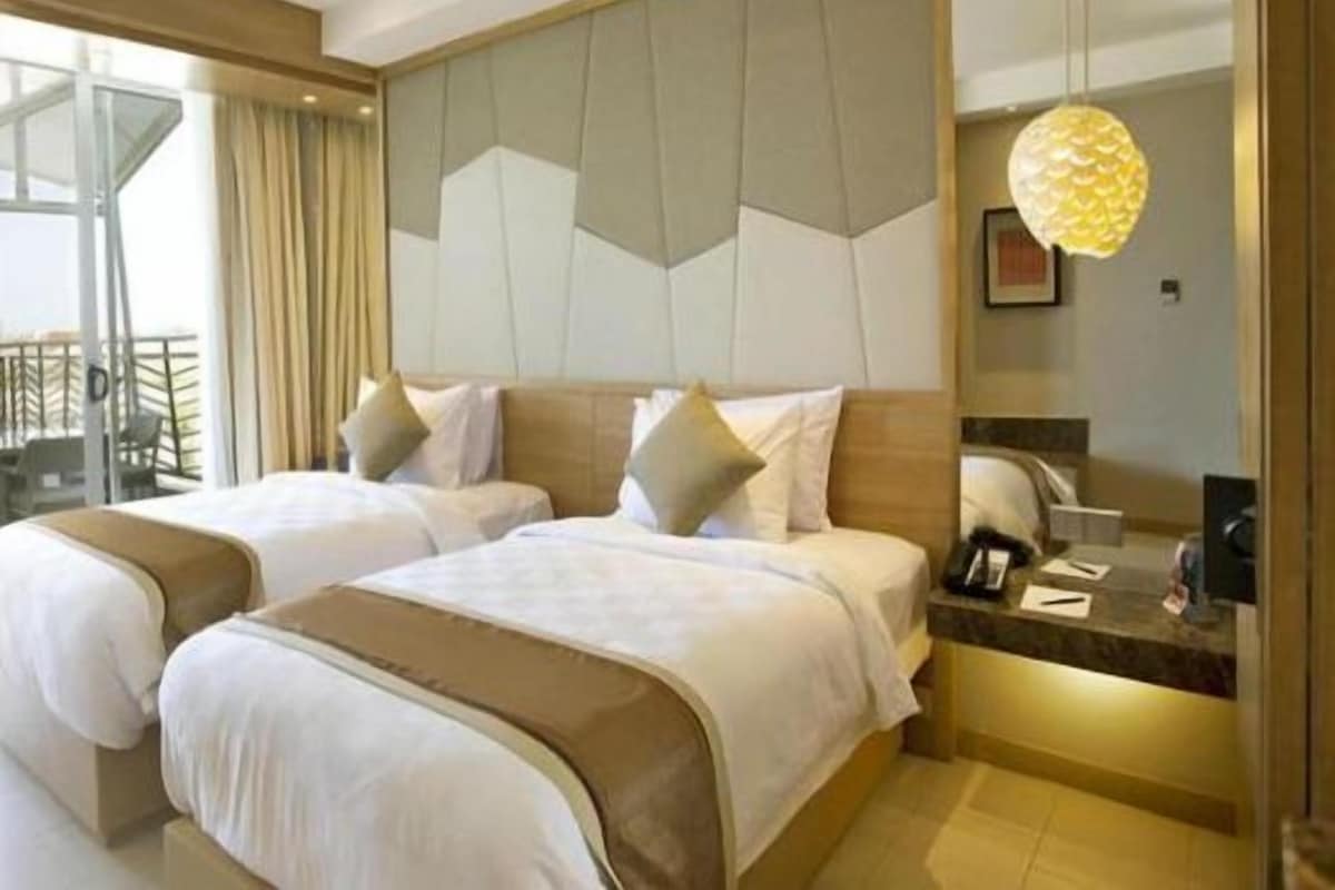 Habitación de hotel con dos camas, un ventanal grande y un candelabro moderno.