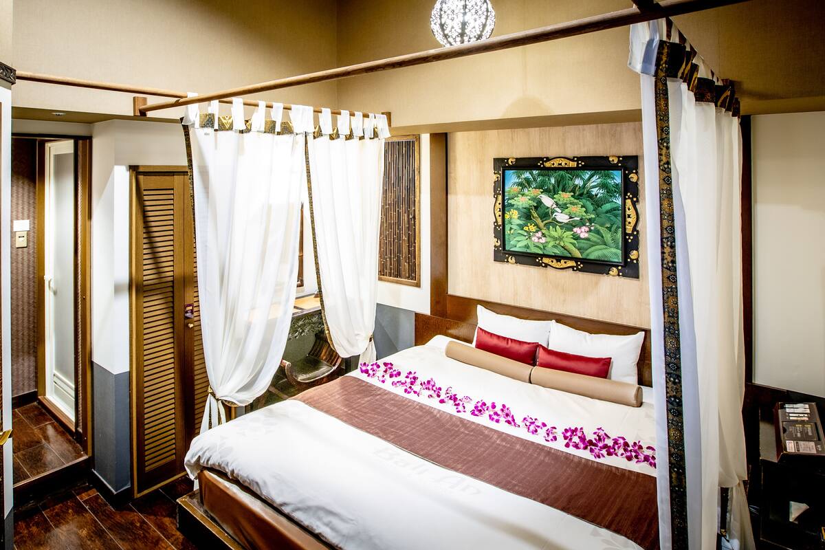 Een hotelkamer met een bed, een schilderij en een gordijn.