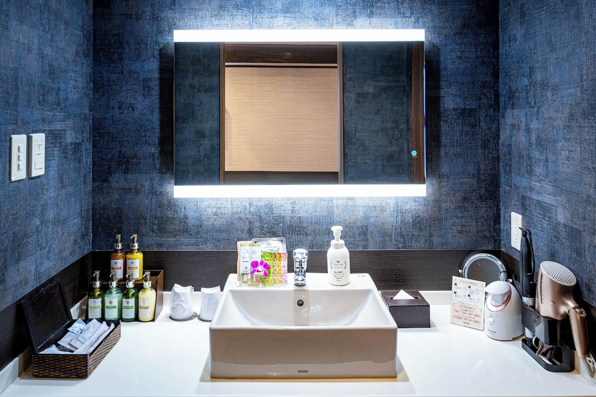 Een moderne badkamer met een grote spiegel, een wastafel en diverse toiletartikelen.