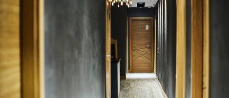 A narrow hallway with a wooden door at the end, a small table, and a ceiling light fixture.