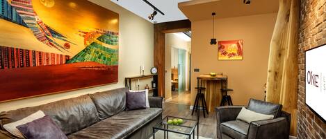 A modern living room with a leather sofa, a coffee table, and a mural on the wall.