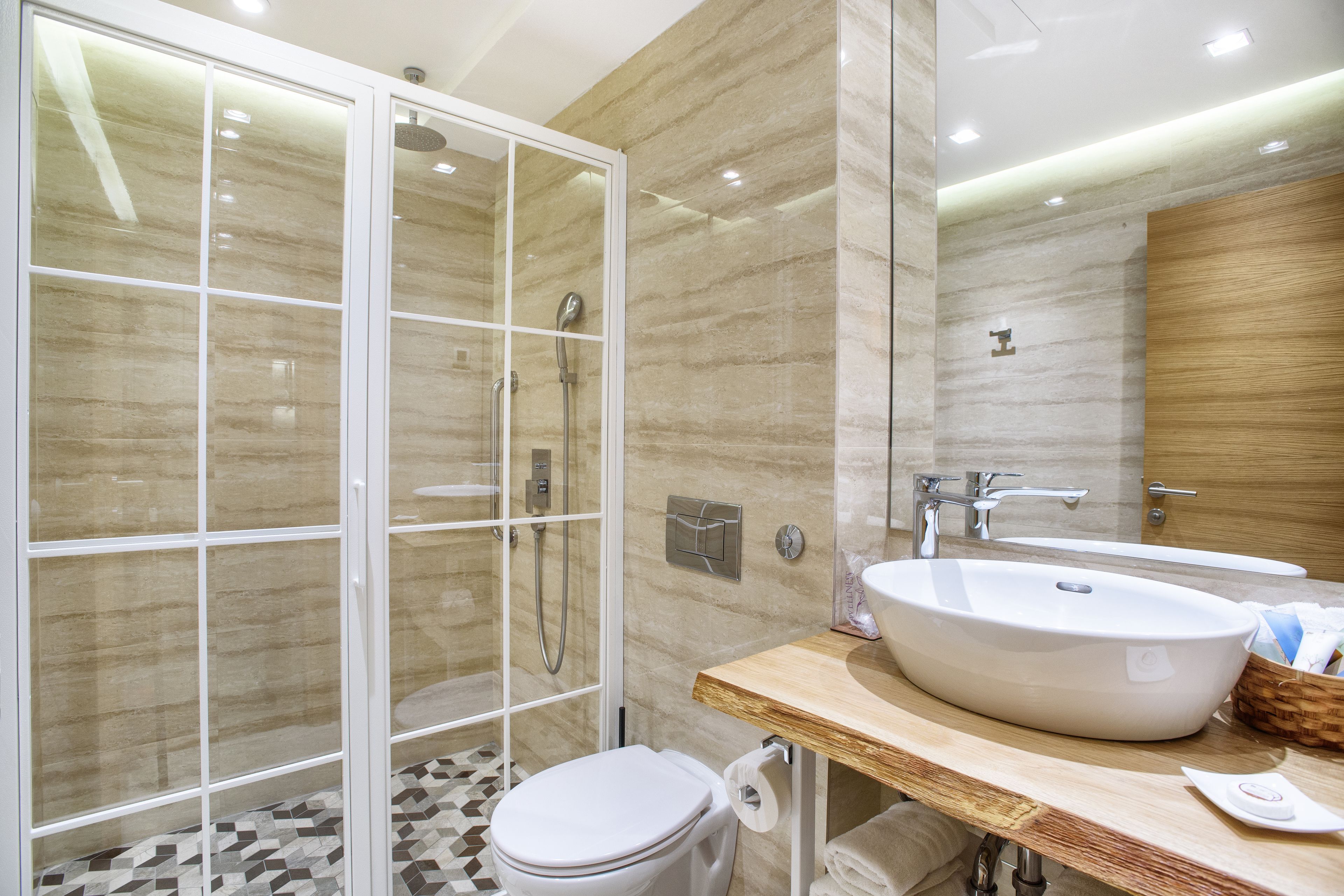 A modern bathroom with a glass shower enclosure, a large sink, and a wooden vanity.