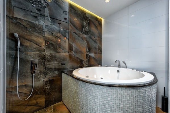 Un baño moderno con una bañera independiente, una ducha y un muro cubierto de azulejos.