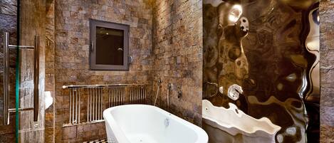 A bathroom with a freestanding bathtub, a glass shower enclosure, and a mirror on the wall.