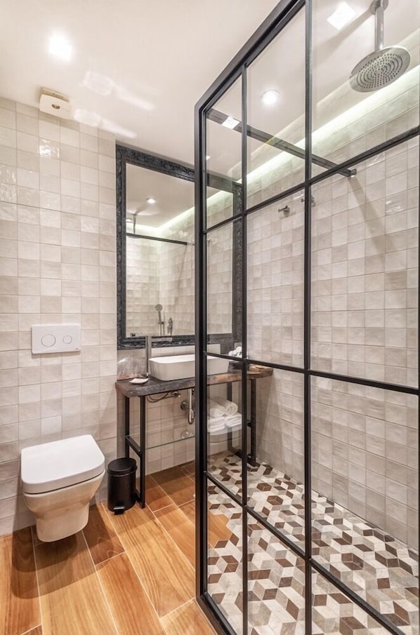A modern bathroom with a glass shower enclosure, a toilet, and a sink. - One Luxury Suites (Belgrade)