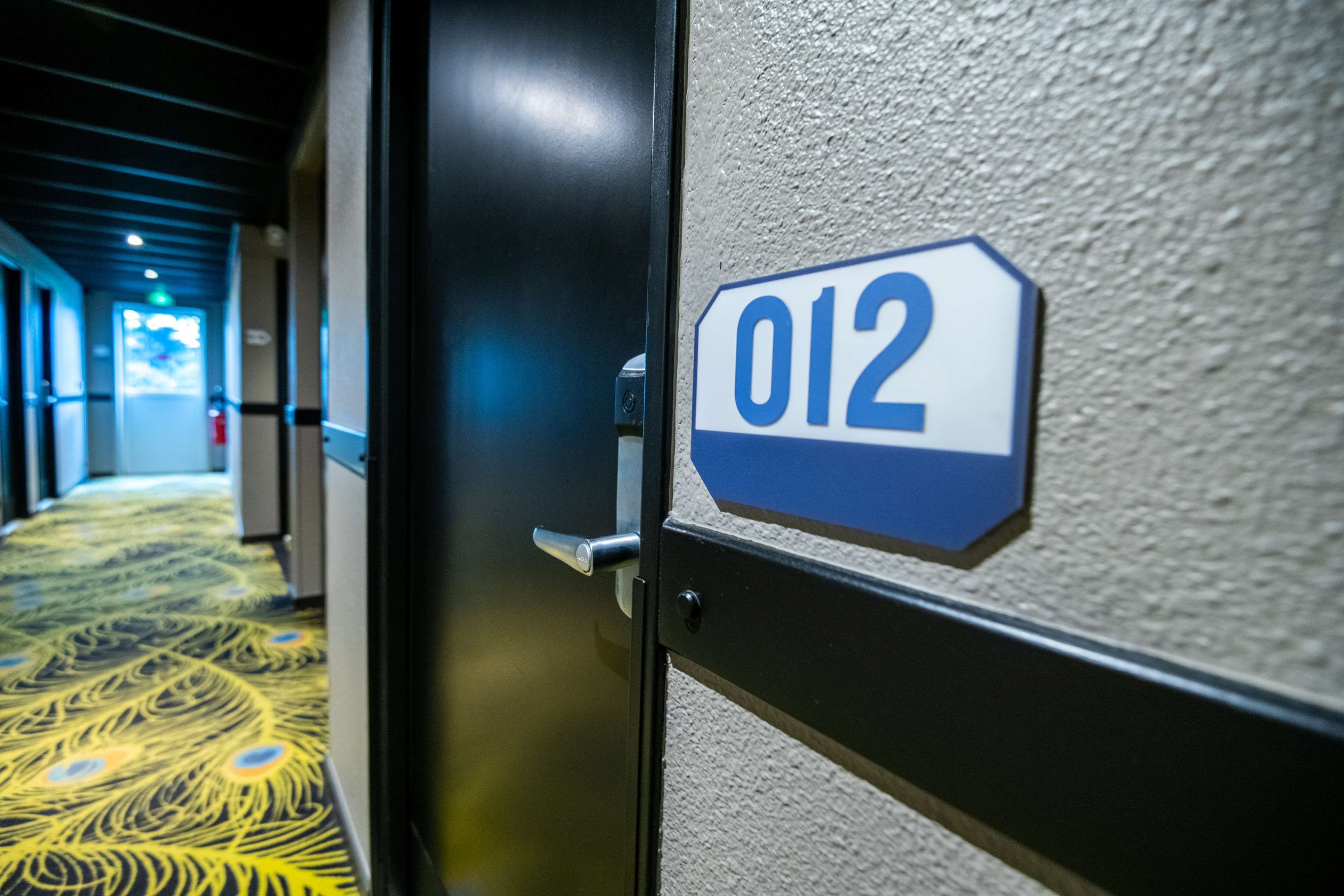 A hotel room door with a number sign '012' indicating the room number.