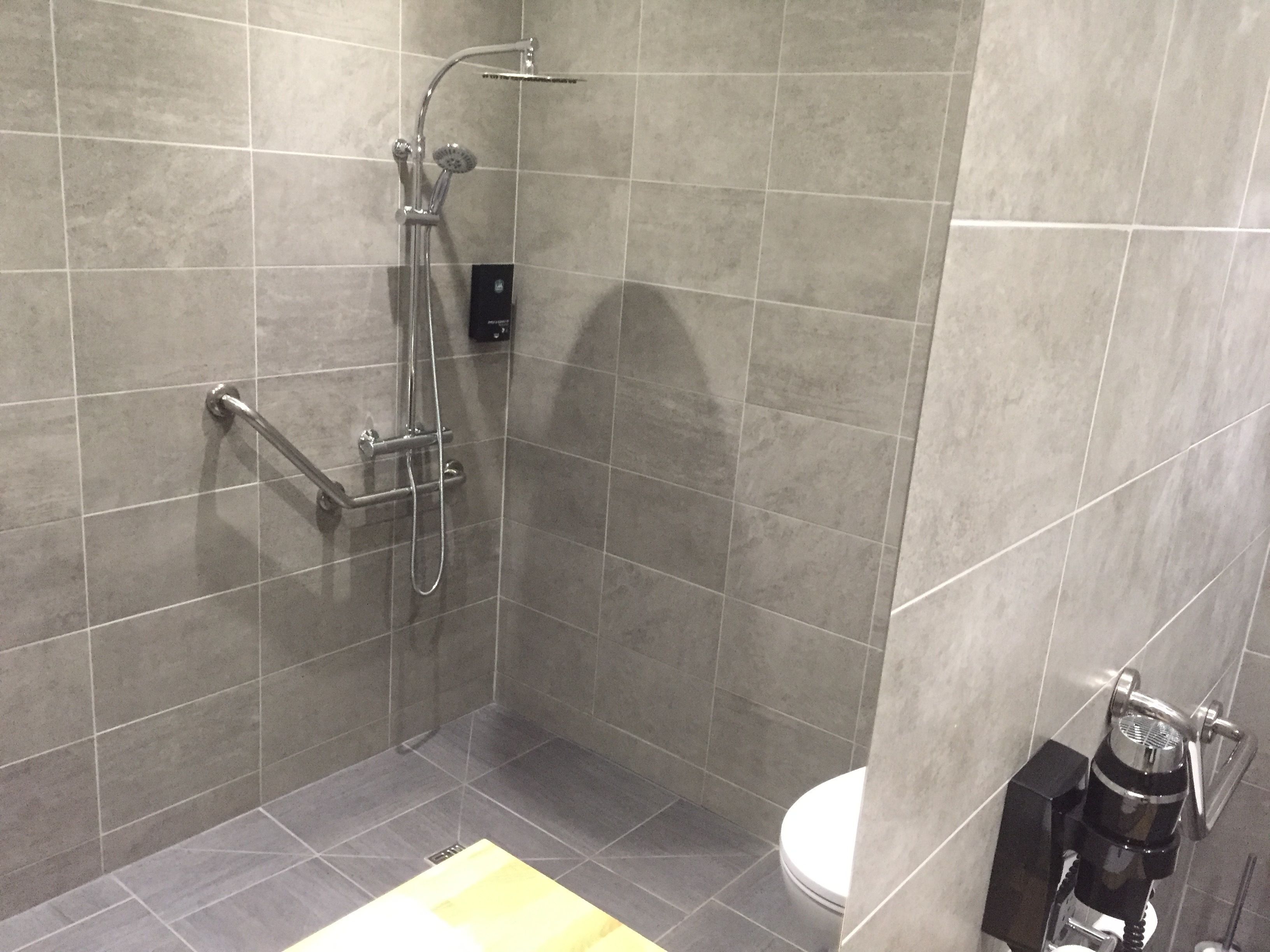 A modern bathroom with a shower, toilet, and a coffee machine.