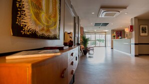 A hotel reception area with a wooden counter, a large abstract painting, and a reception desk. - KYRIAD BORDEAUX SUD - Villenave d'Ornon (Villenave-d'Ornon)