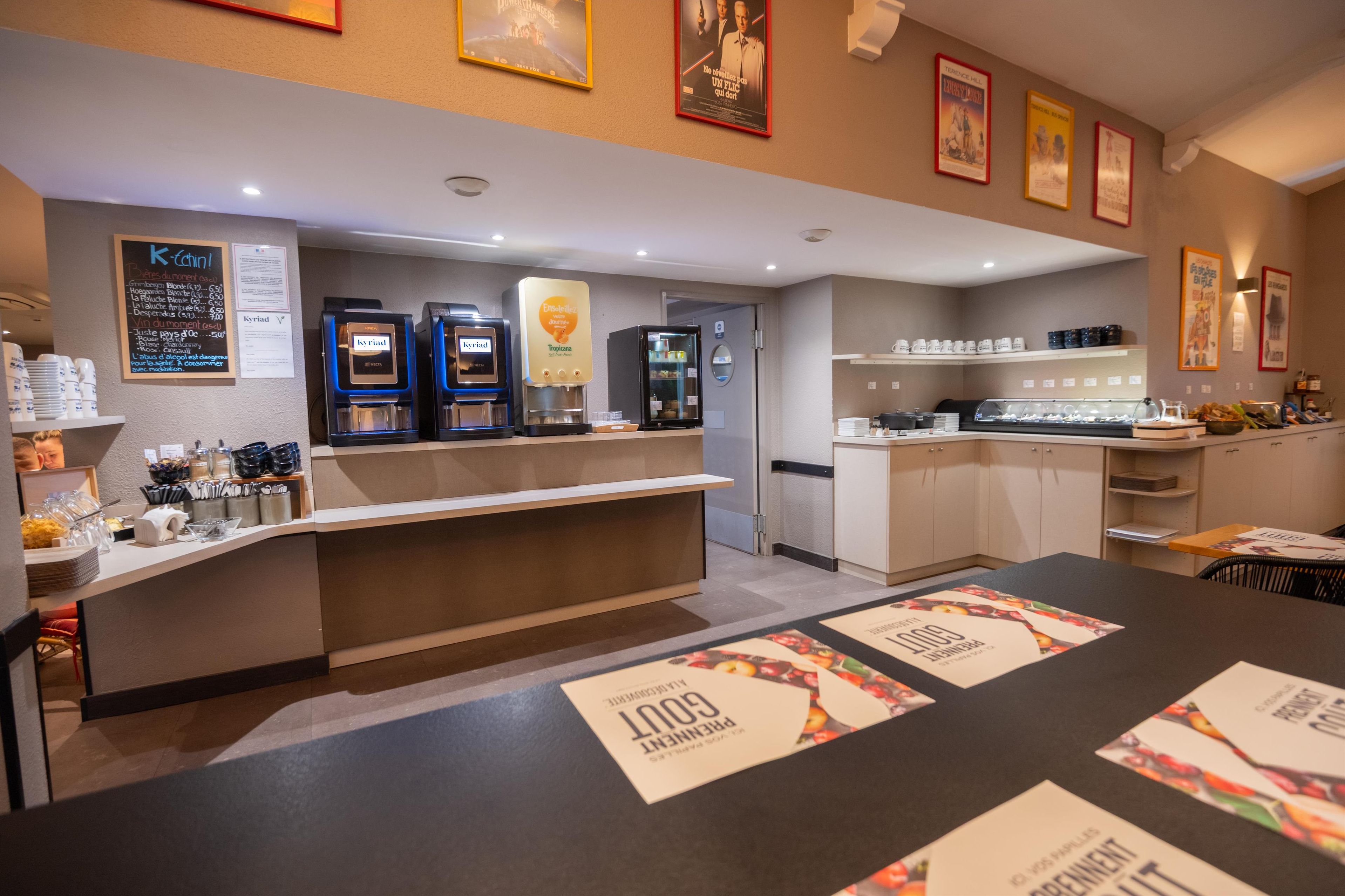 A hotel reception area with a counter, coffee machines, and a menu board.