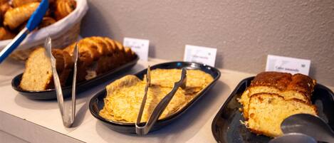 A display of baked goods, including bread and pastries, arranged on a counter with price tags.