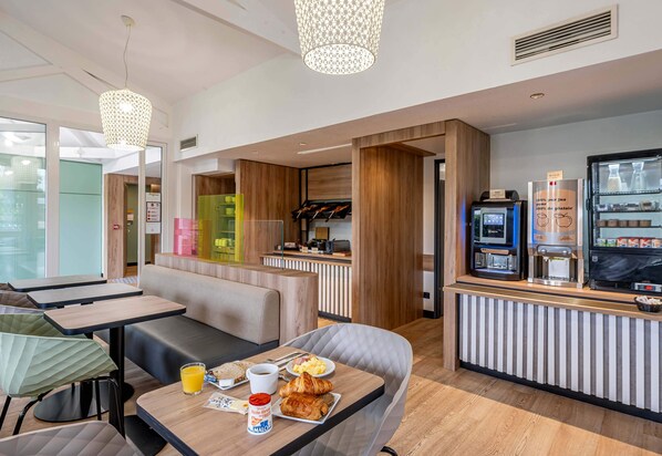 A modern dining area with a counter, seating, and a coffee machine.