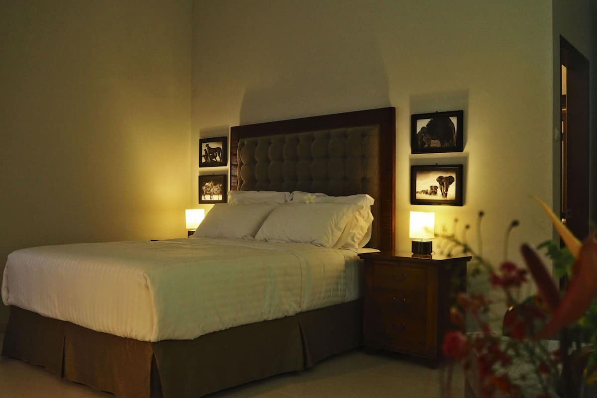 A neatly made bed with a wooden headboard, bedside tables with lamps, and framed pictures on the walls.