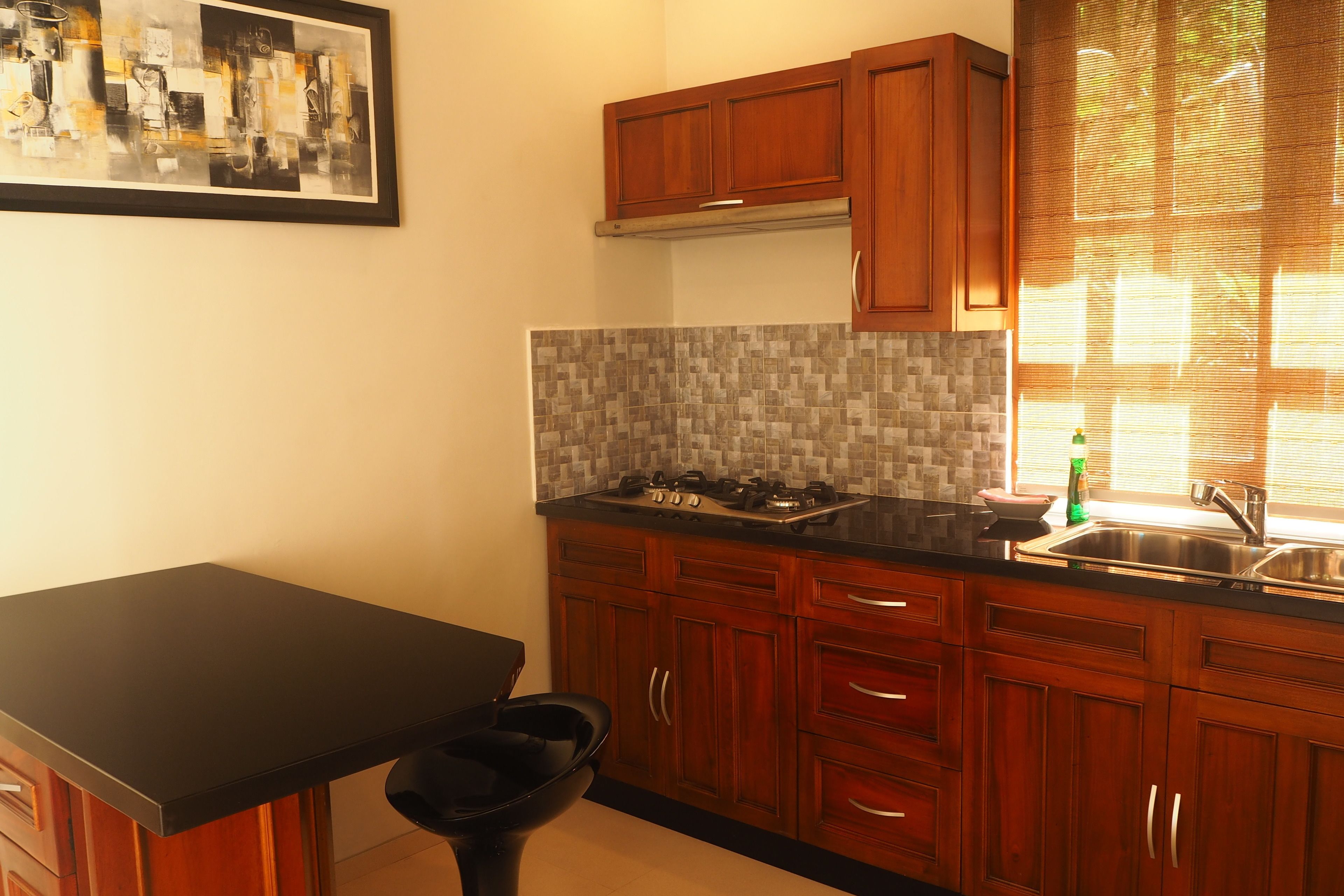 A kitchen with wooden cabinets, a black countertop, and a tiled backsplash.