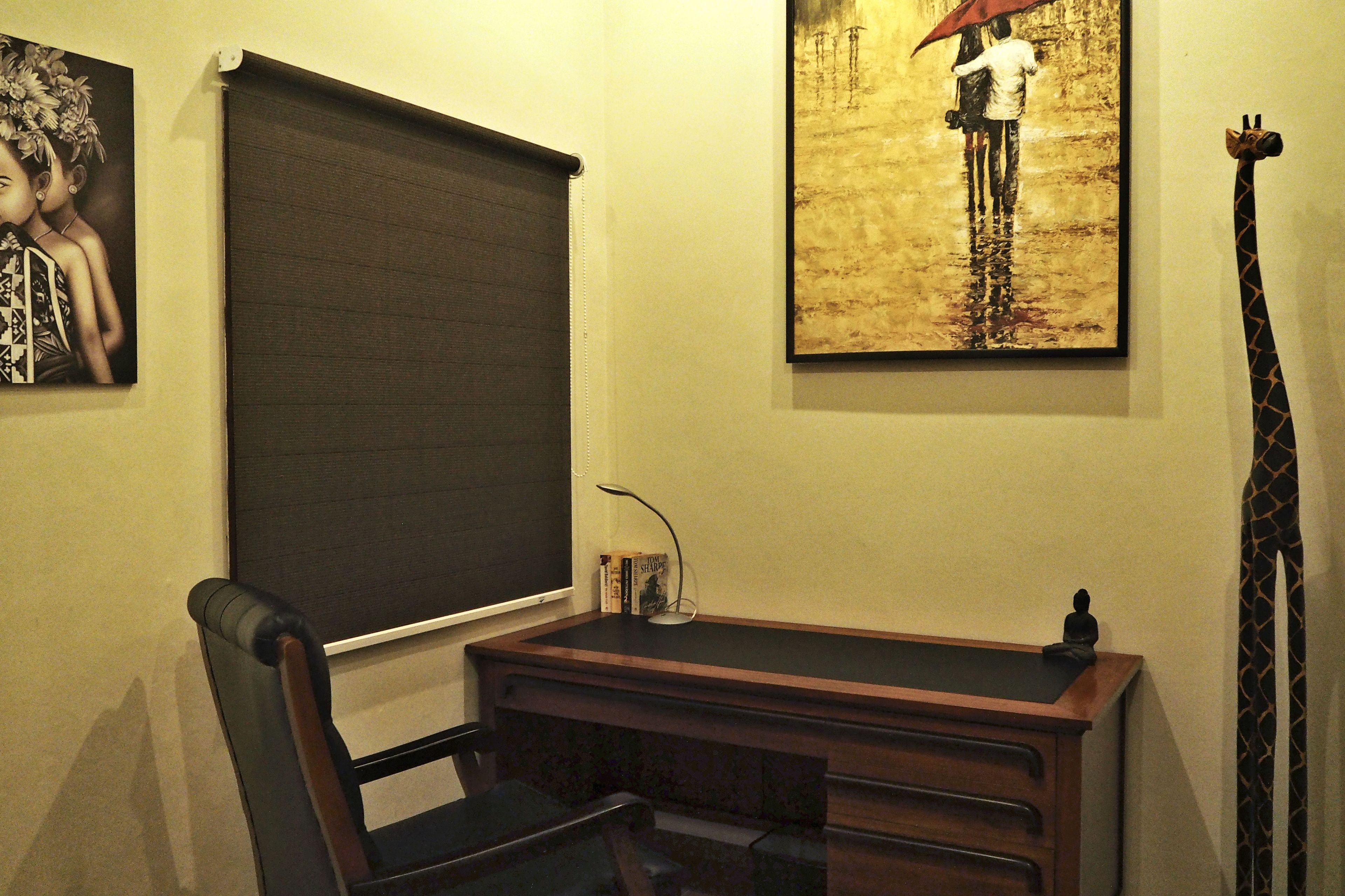 A room with a desk, chair, bookshelf, and a giraffe statue.