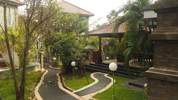 Un patio con un sendero curvo, palmeras y un edificio de techo de tejas.