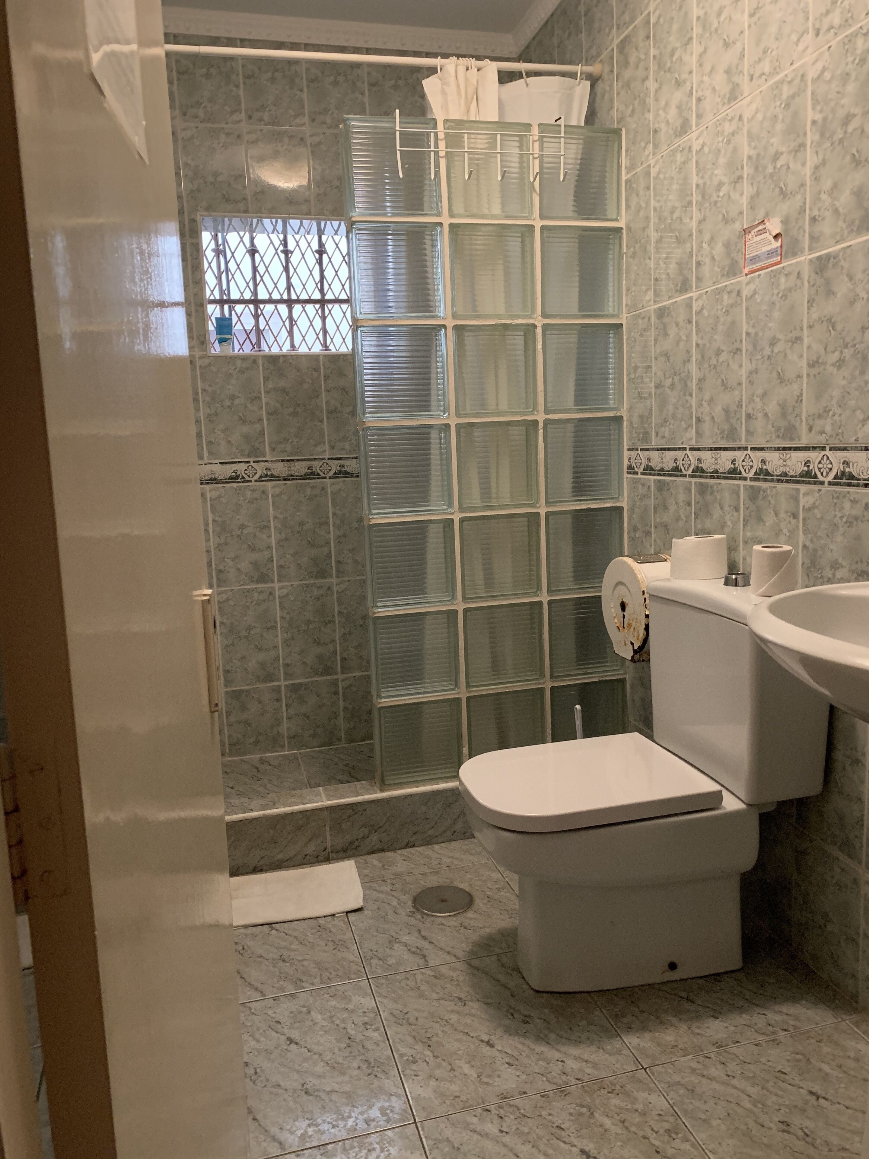 Un baño con cabina de ducha de vidrio, inodoro y lavamanos.