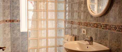 Un baño con inodoro, lavabo y zona de ducha.
