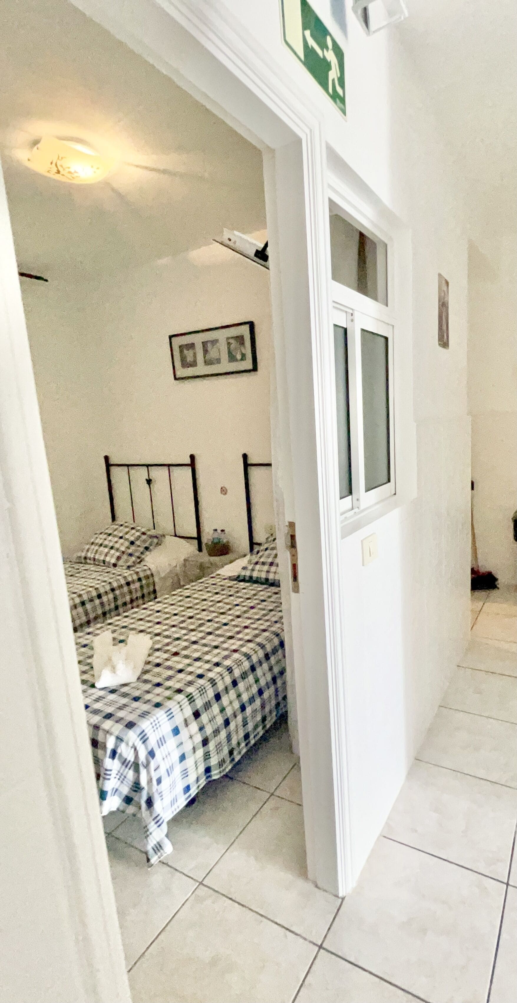Una habitación con una cama, una ventana y una puerta que da a otra habitación.