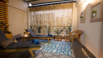 Une pièce dotée d’une grande fenêtre, d’un tapis à motifs et d’un coin salon avec un canapé et des fauteuils.