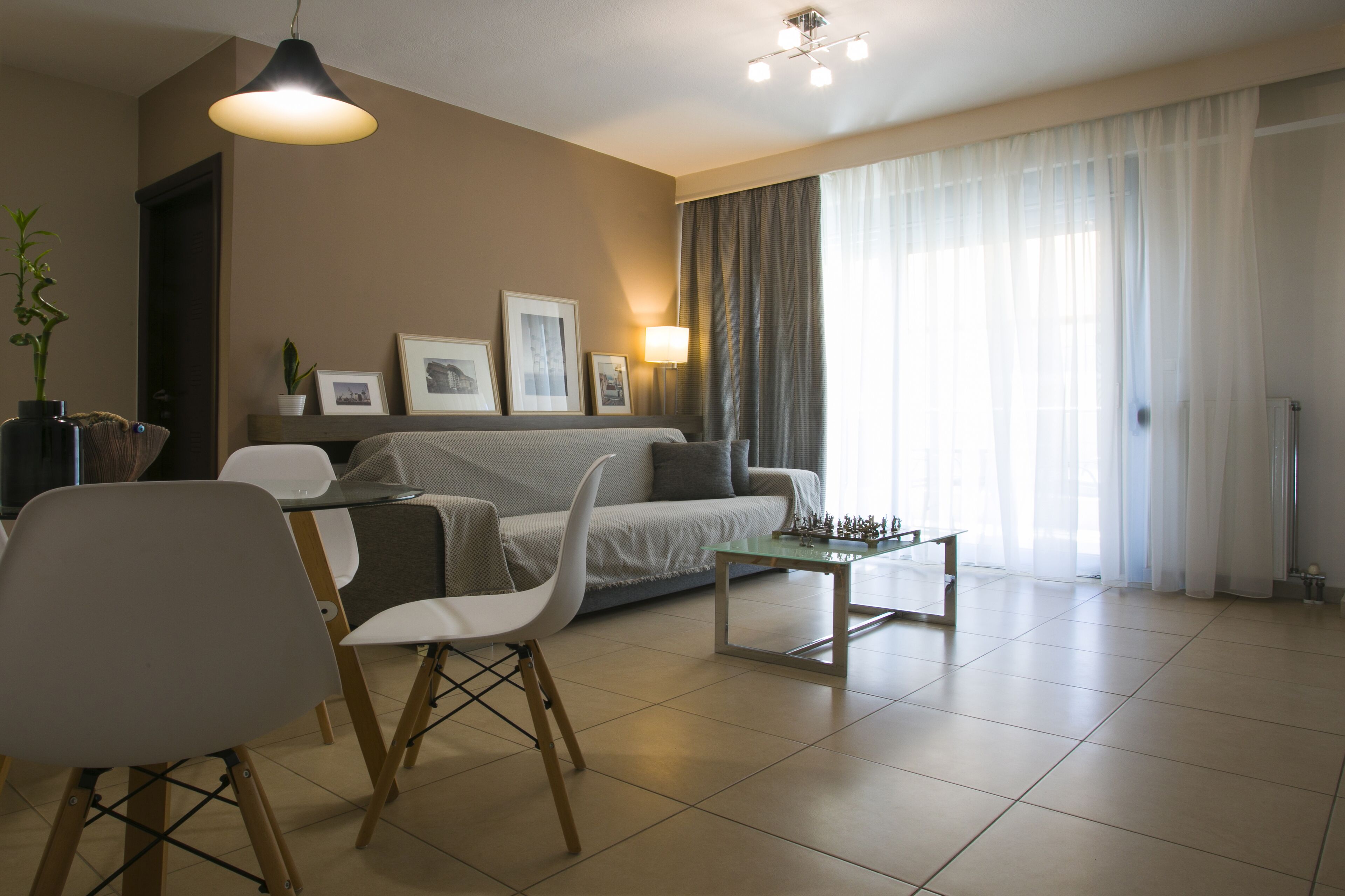 Una sala de estar moderna con un sofá, sillas, una mesa de centro y una lámpara.