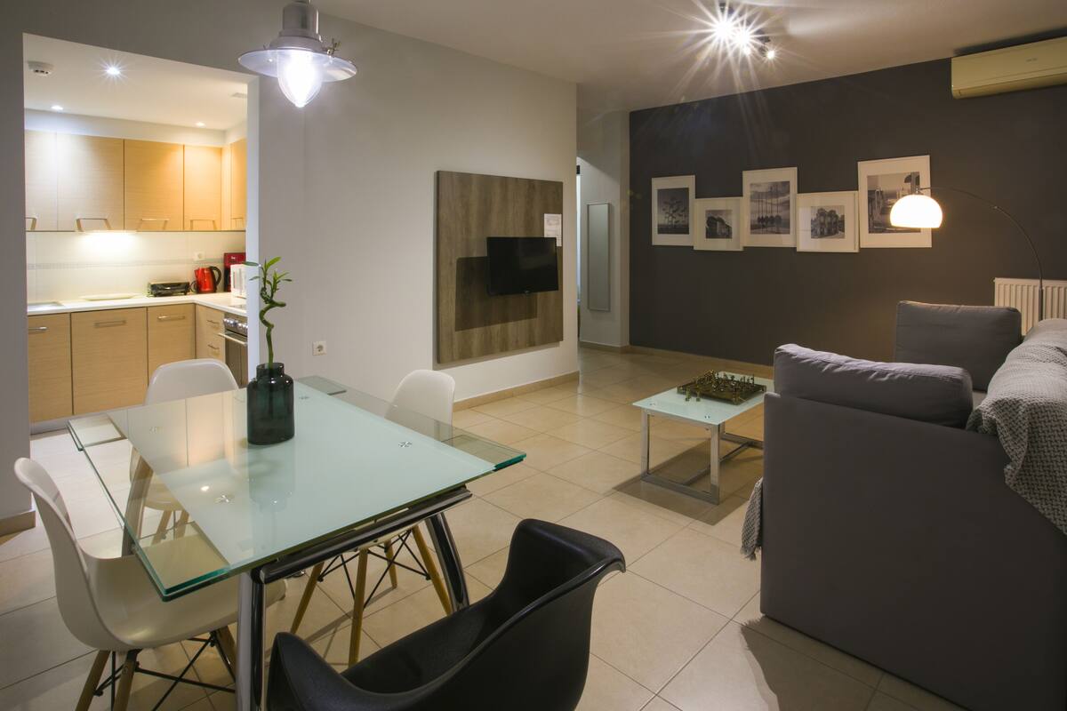 A modern living room with a glass dining table, a sofa, and a coffee table.