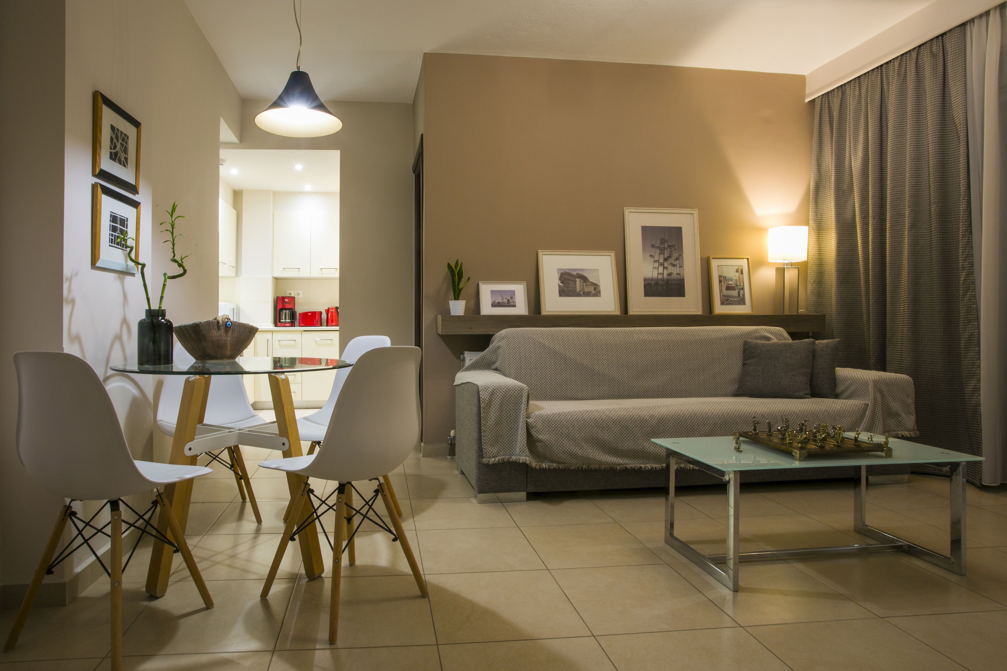 Una sala de estar moderna con un sofá, una mesa de centro de vidrio y un comedor con sillas.