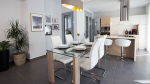 A modern kitchen with white cabinets, a stainless steel range hood, and a built-in microwave. - Polis Apartments (Thessaloniki)