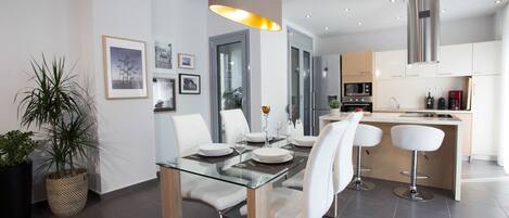Una cocina moderna con armarios blancos, una campana extractora de acero inoxidable y un microondas integrado.