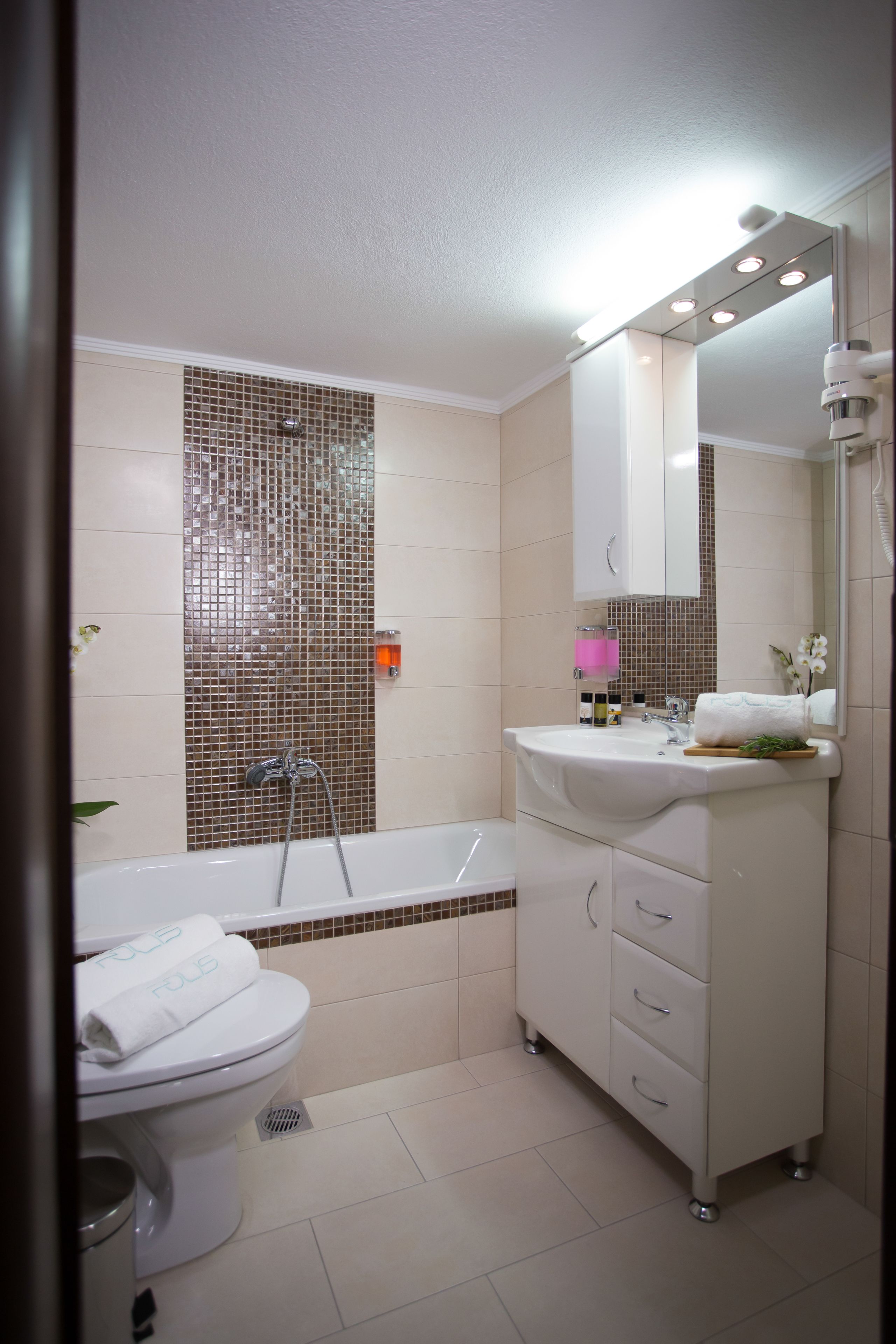 Een moderne badkamer met een bad, toilet, wastafel en een grote spiegel.
