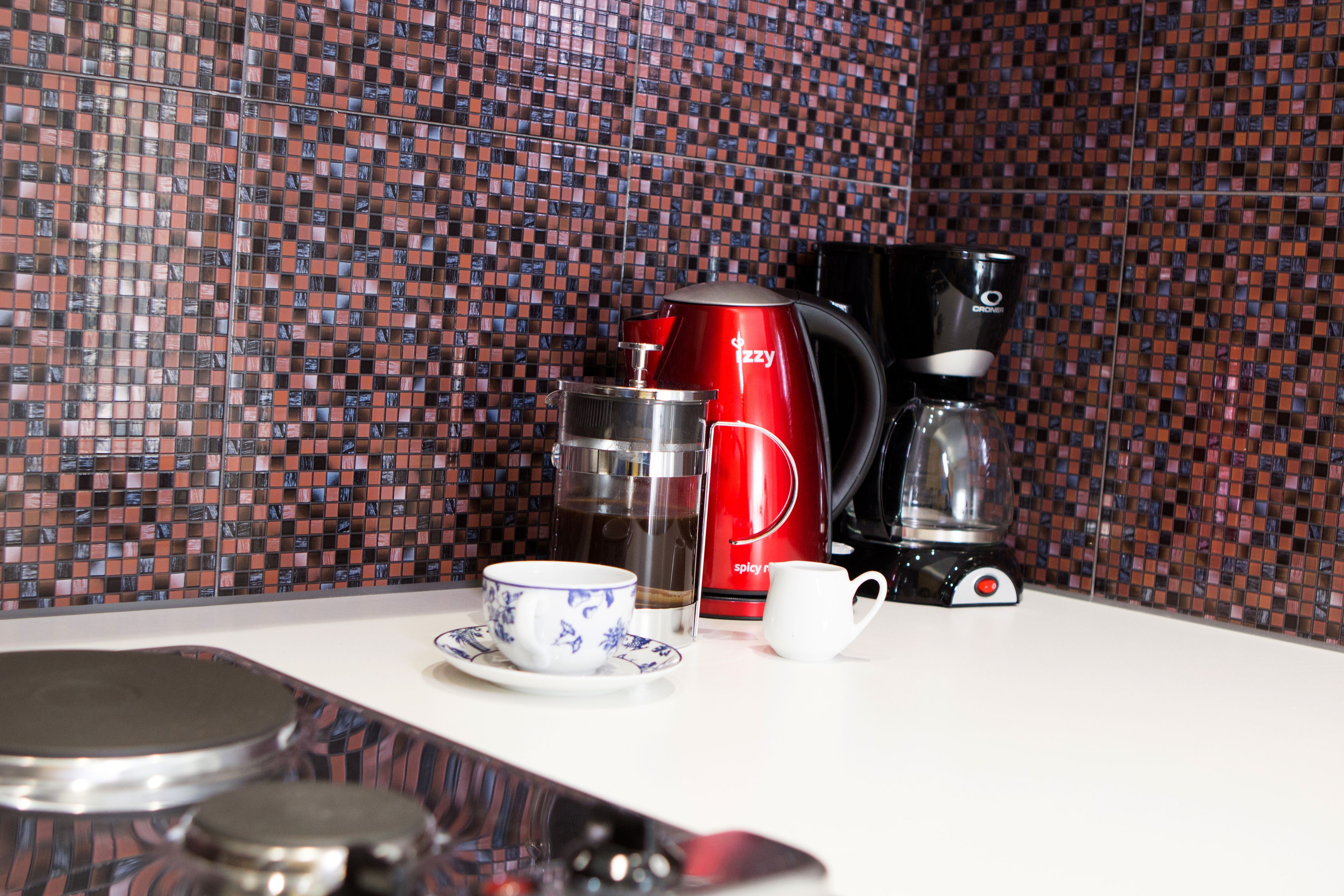 Una encimera de cocina con una cafetera, una taza y un vaso.