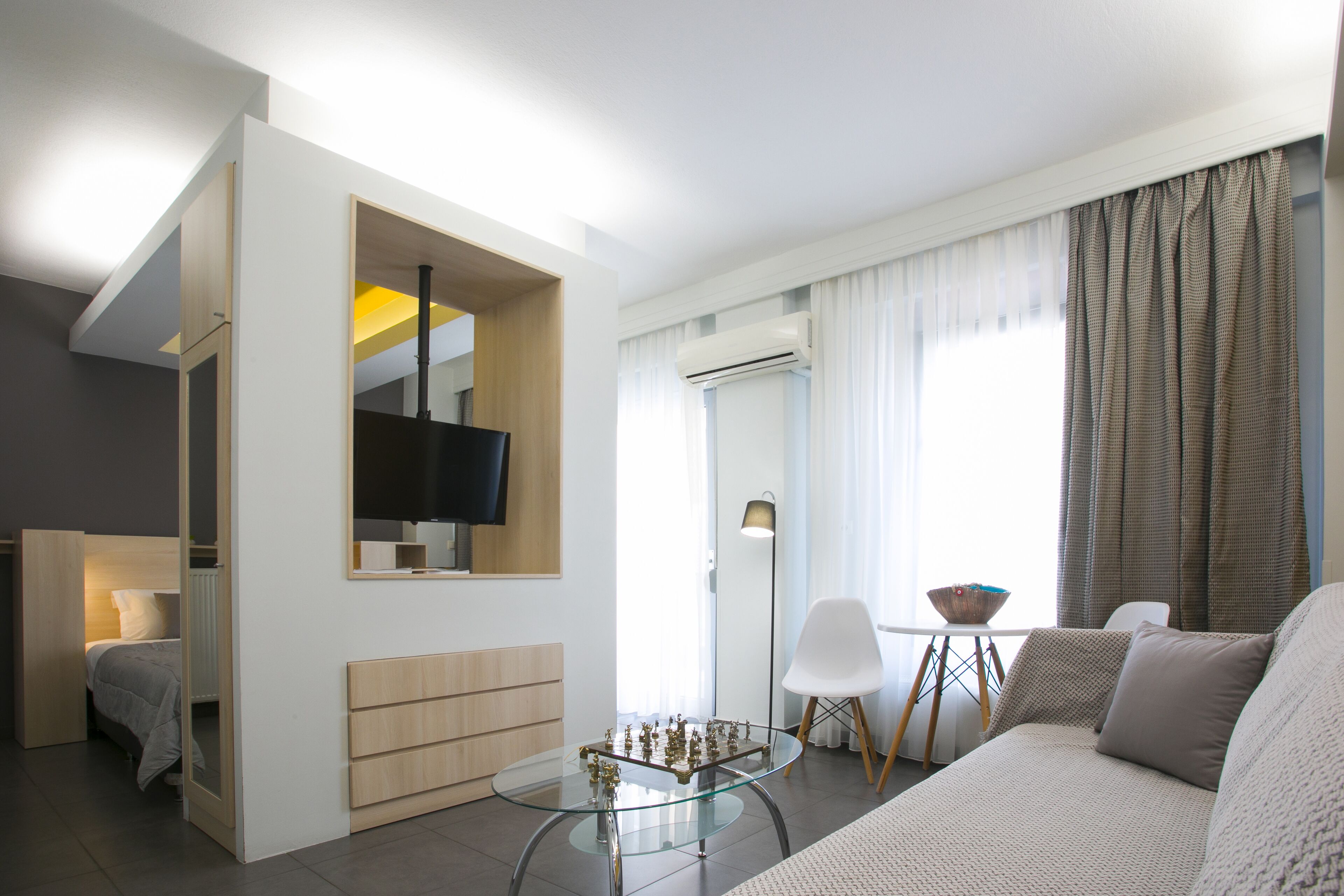 Een moderne woonkamer met een glazen salontafel, een bank, een televisie en een eethoek met een tafel en stoelen.