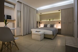 A modern bedroom with a bed, bedside table, chair, and a small table with a plant. - Polis Apartments (Thessaloniki)
